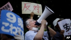 A man shouts during a protest at the Japanese prime minister's office about the Japanese government's plan to reinterpret the constitution to permit Japan's military a larger international role.