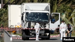 Investigators near the heavy truck that ran into a crowd at high speed, killing 84 people who were celebrating the Bastille Day, July 14 national holiday on the Promenade des Anglais in Nice, France, July 15, 2016. 