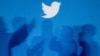 Archivo - Las sombras de las personas que sostienen teléfonos móviles se proyectan sobre un fondo con el logotipo de Twitter en esta imagen ilustrativa tomada en Varsovia el 27 de septiembre de 2013.