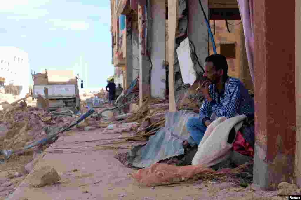 A man sits next to damaged buildings impacted by fatal floods in Derna, Libya, Sept. 28, 2023.