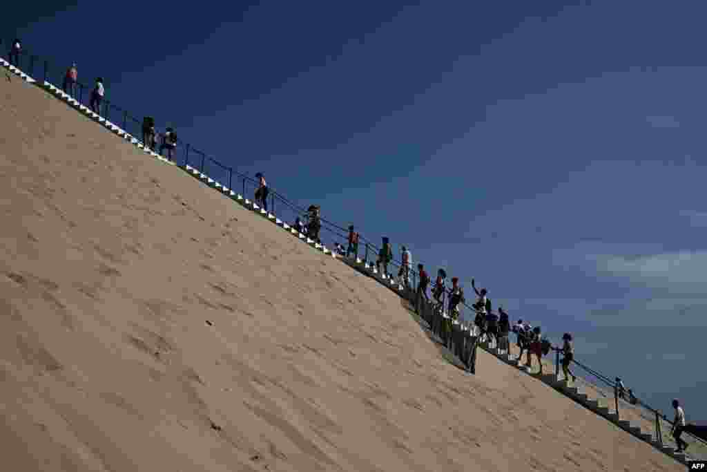 Visitors walk the stairs of the dune of Pilat, the tallest sand dune in Europe, in Pyla sur Mer, southwestern France.