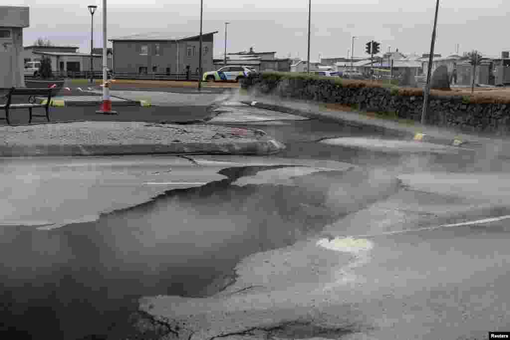 Smoke rises from the crack in a road in the fishing town of Grindavik, which was evacuated due to volcanic activity, in Iceland.