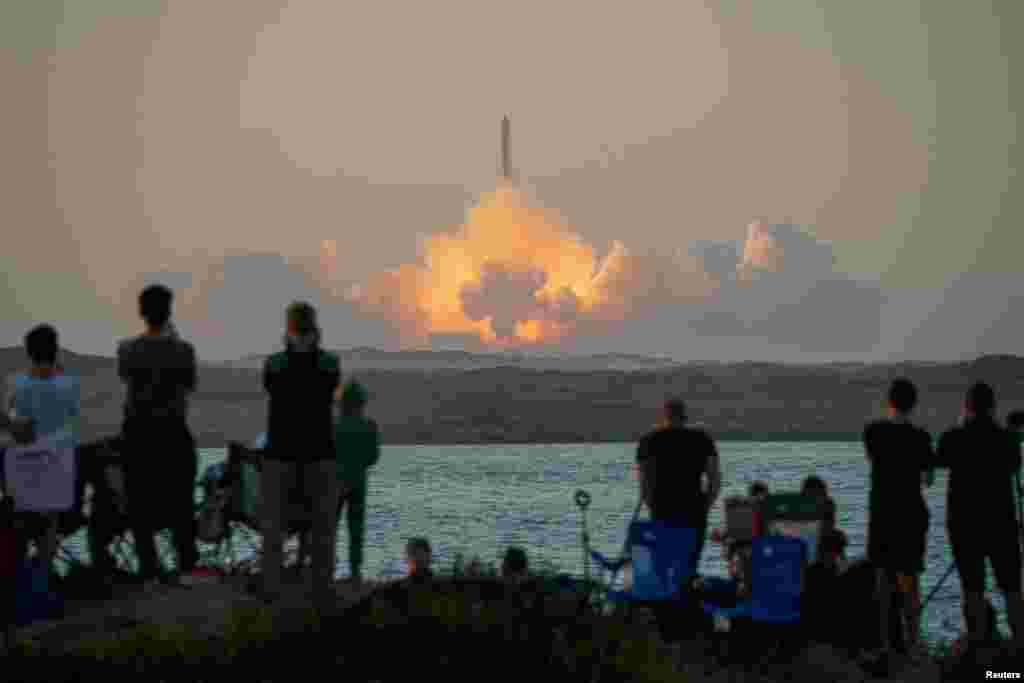 People watch as SpaceX's next-generation Starship spacecraft atop its powerful Super Heavy rocket lifts off from the company's Boca Chica launchpad during a test flight, as seen from South Padre Island, near Brownsville, Texas, Nov.18, 2023.