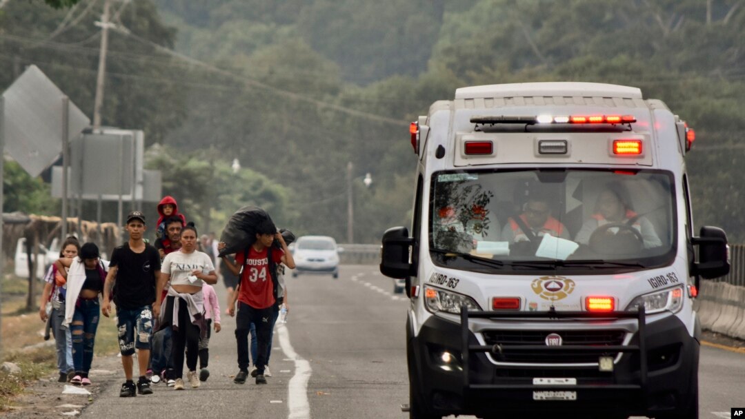 Una ambulancia pasa junto a migrantes que caminan hacia Huehuetán, estado de Chiapas, México, el lunes 24 de abril de 2023.