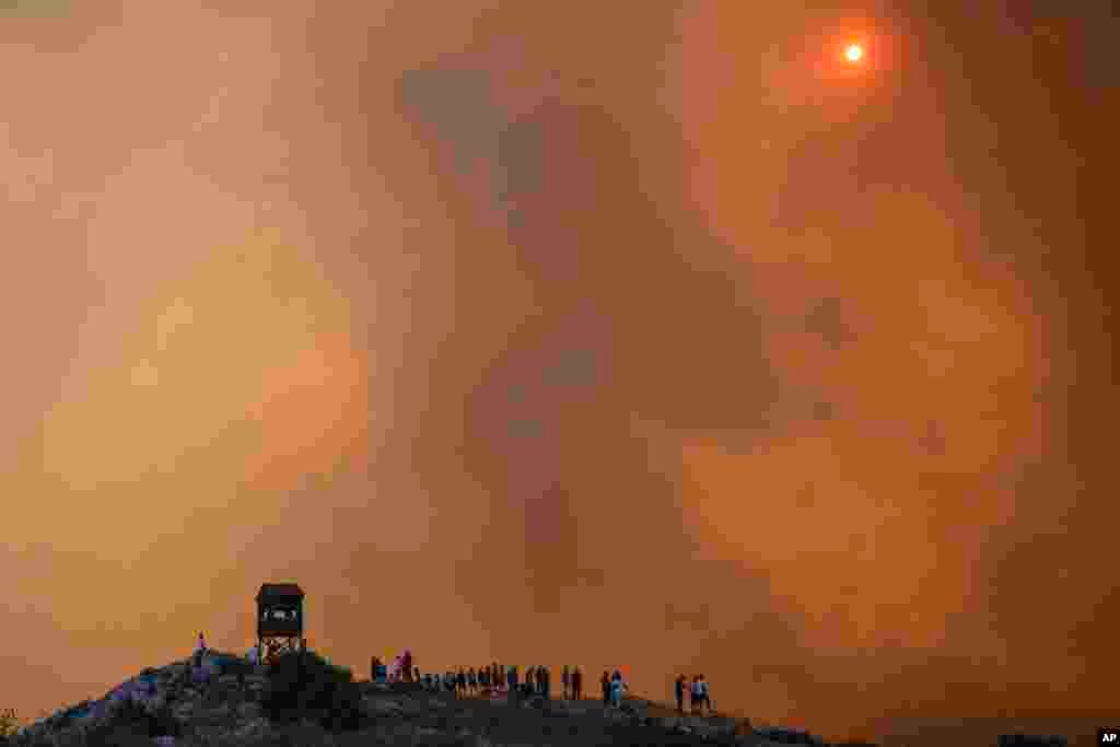 People watch a wildfire in Mandra west of Athens, Greece.