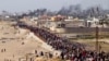 Palestinos esperan a que los camiones de ayuda crucen en el centro de la Franja de Gaza el 19 de mayo de 2024.