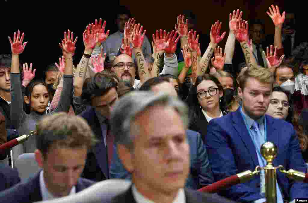 Anti-war protesters raise their "bloody" hands behind U.S. Secretary of State Antony Blinken during a Senate Appropriations Committee hearing on President Biden's $106 billion national security supplemental funding request to support Israel and Ukraine, as well as bolster border security, on Capitol Hill in Washington.