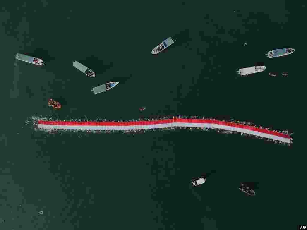 An aerial photo shows 145 swimmers taking part in an effort to stretch a 78-meter-long national flag in the sea ahead of Indonesia's 78th Independence Day in Makassar, South Sulawesi, Aug. 12, 2023.