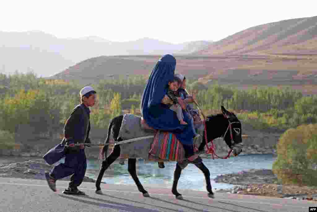 An Afghan burqa-clad woman with children ride a donkey in Kishim district of Badakhshan province.