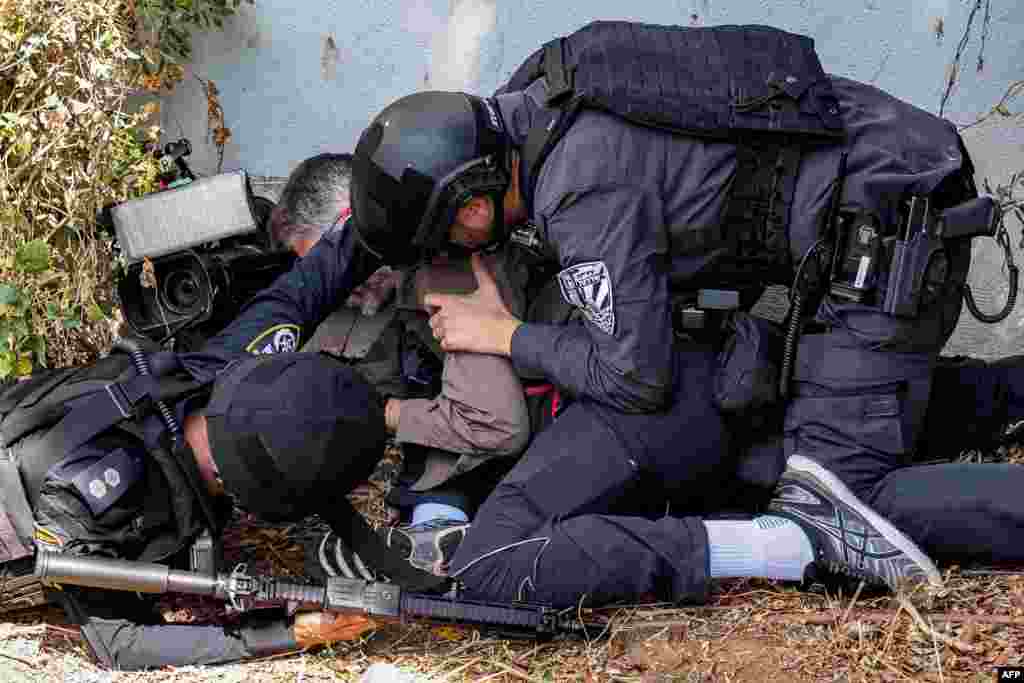 Israeli police and security forces assist a journalist taking cover during an alert for a rocket attack in Israel's southern city of Sderot near the border with Gaza.