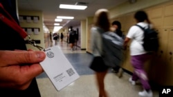 FILE - Brent Kiger, Olathe Public Schools' director of safety service, displays a panic-alert button while students at Olathe South High School rush between classes, Aug. 19, 2022, in Olathe, Kansas. (AP Photo/Charlie Riedel, File)