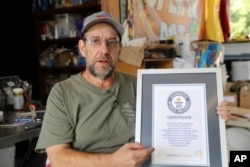 Ed Currie holds up his certification that his new Pepper X variety of peppers is the hottest in the world according to the Guinness Book of World Records on Tuesday, Oct. 10, 2023, in Fort Mill, S.C. (AP Photo/Jeffrey Collins)