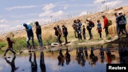 Migrantes que buscan asilo cruzan el Río Bravo para regresar a México desde Estados Unidos, luego de que miembros de la Guardia Nacional de Texas extendieran alambre de púas para impedir que cruzaran, visto desde Ciudad Juárez, México, el 13 de mayo de 2023.