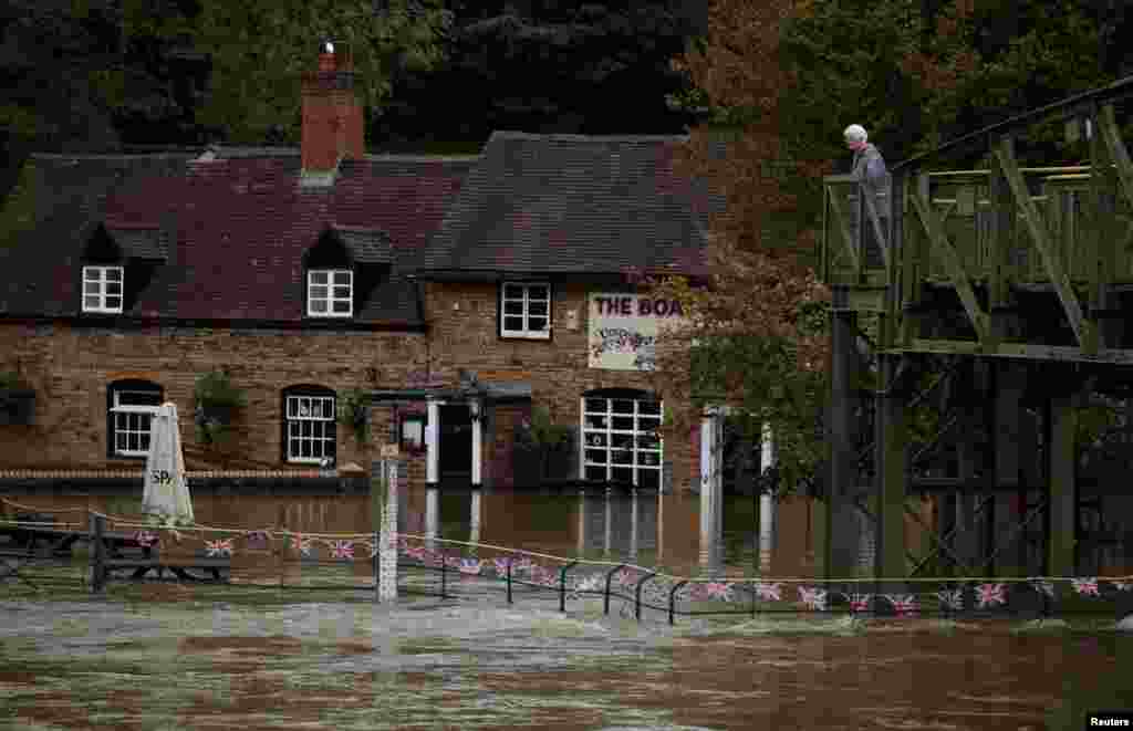 A woman looks out over the flooded beer garden of the Boat Inn after the River Severn burst its banks near Ironbridge, Britain, Oct. 23, 2023.