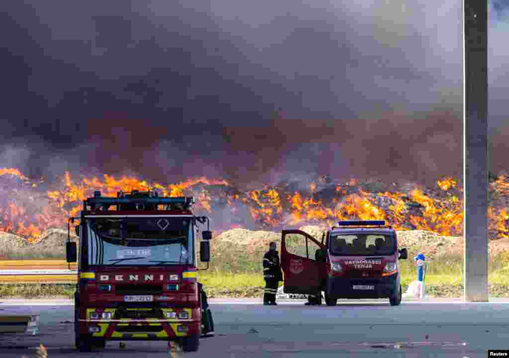 A firefighter stands near the fire at Drava International factory near Osijek, Croatia. A large fire at a plastics depot has spread to a nearby building where chemicals were stored, releasing toxic fumes that could pose ecological risks as strong winds began to carry them south, officials said.