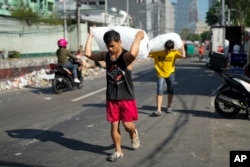 FILE - Men deliver sacks of ice cubes as demand remains high due to hot temperatures in Quezon city, Philippines on April 24, 2024. (AP Photo/Aaron Favila, File)