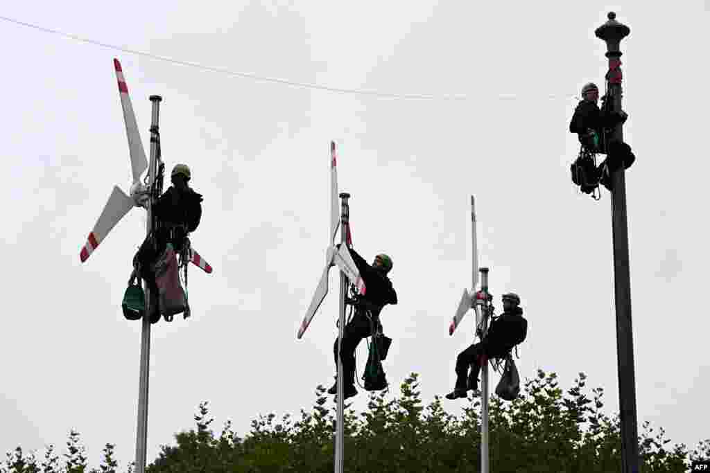 Greenpeace activists climb up flagpoles to fix mockups of wind turbines in front of the Bavarian State Chancellery in Munich, southern Germany, as they call for more wind power.