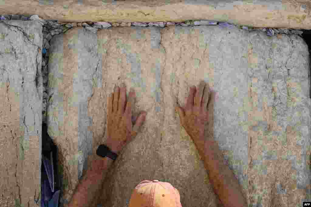 A Jewish man touches the wall as he prays at the Western Wall, the last remaining vestige of the Second Temple, in Jerusalem's Old City, amid the ongoing battles between Israel and the Palestinian Islamist group Hamas.