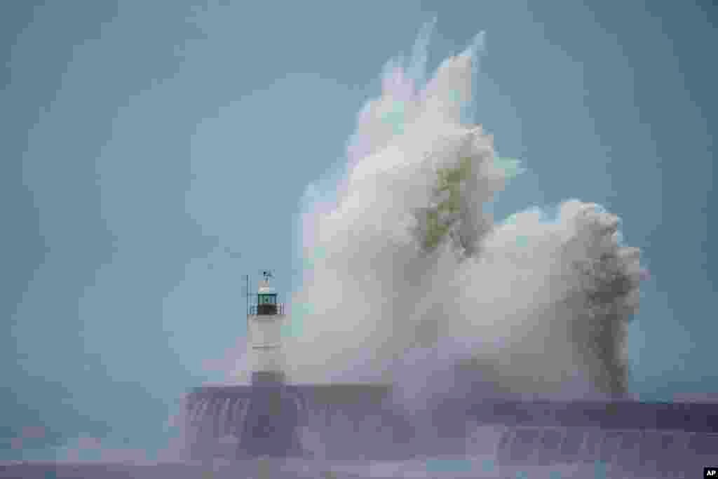 Waves crash over Newhaven Lighthouse and the harbor wall in Newhaven, southern England.