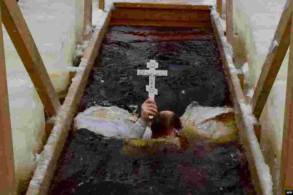 An Orthodox priest plunges into the icy waters of a lake during the celebration of the Epiphany holiday in the village of Orlino, Leningrad region, Russia. Among Orthodox Christians, the feast of Epiphany celebrates the day the spirit of God descended upon believers in the shape of a dove during Jesus Christ's baptism in the river Jordan. 