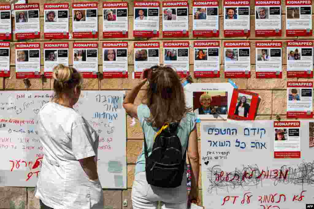 People look at posters showing the pictures of Israeli hostages held by Palestinian militants since the October 7 attack, near Azrieli Mall in Tel Aviv.