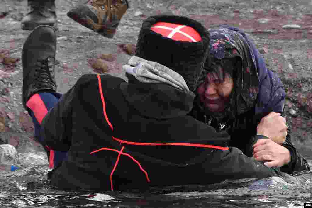 A cossack helps a woman get out of the Kara-Balta river during the celebration of the Epiphany holiday near the village of Sosnovka, some 90 kms from Bishkek, Kyrgyzstan. Among Orthodox Christians, the feast of Epiphany celebrates the day the spirit of God descended upon believers in the shape of a dove during Jesus Christ's baptism in the river Jordan. 
