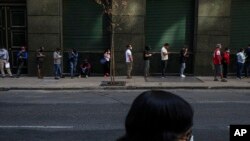 Personas hacen fila para cobrar el seguro de desempleo, muchos de ellos afectados por la crisis económica provocada por la propagación del nuevo coronavirus, en el centro de Santiago de Chile, el lunes 6 de abril de 2020.