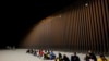 Migrantes esperando junto al final de un tramo de frontera el martes 23 de agosto de 2022 cerca de Yuma, Airzona.