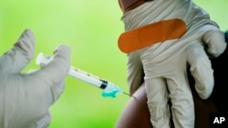 A health worker gives a dose of COVID-19 vaccine in Reading, Pa. COVID-19 vaccinations are at a critical juncture as companies test whether new approaches can keep up with a mutating coronavirus — even though it’s not clear if any change is needed. (AP Photo/Matt Rourke, File)