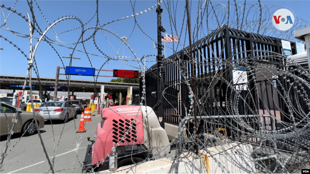 El alambre de púa sobresale en la línea fronteriza entre México y Estados Unidos, en la garita fronteriza de Otay, donde a lo lejos se puede ver ondeando la bandera estadounidense.(Tijuana, México-Abril 4, 2022-Celia Mendoza)