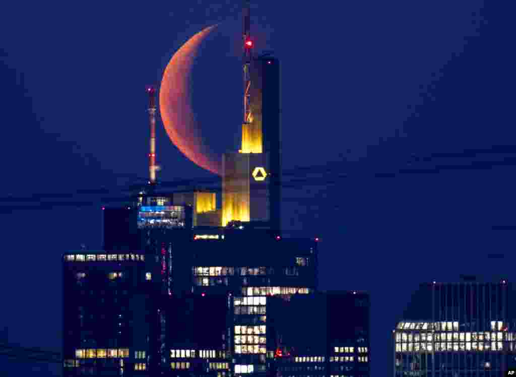 The moon rises behind the buildings of the banking district in Frankfurt, Germany.