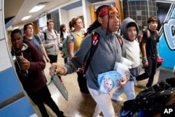 FILE - Students at the Washington Junior High School leaving classes for the day, use the unlocking mechanism to open the bags their cell phones were sealed in during the school day on Oct. 27, 2022. (AP Photo/Keith Srakocic