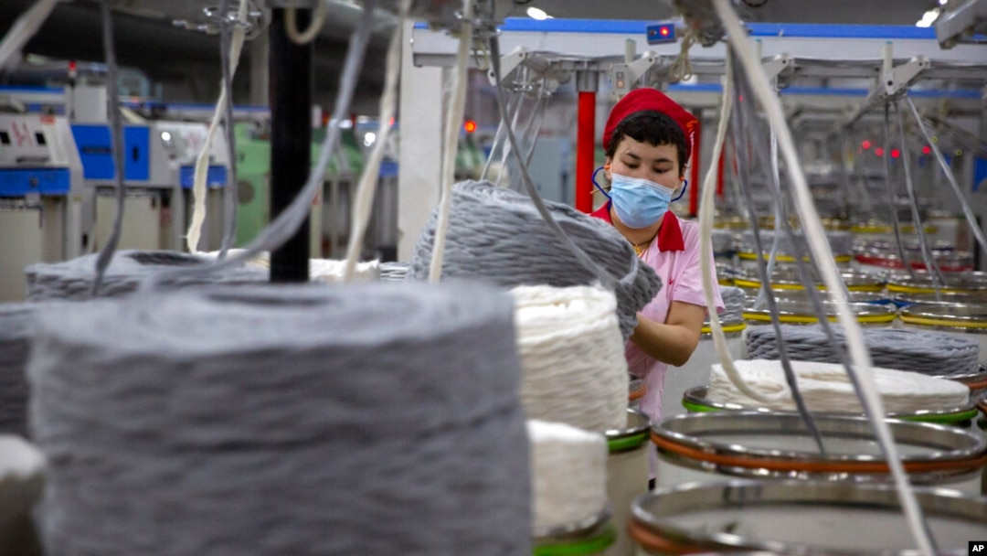中國新疆維吾爾自治區阿克蘇市的一名工人正在紡織廠收集棉紗。（2021年4月20日）