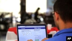 A man demonstrates how he enters his Facebook page as he works on his computer at a restaurant in Brasilia, Brazil, Thursday, Jan. 4, 2018. (AP Photo/Eraldo Peres)
