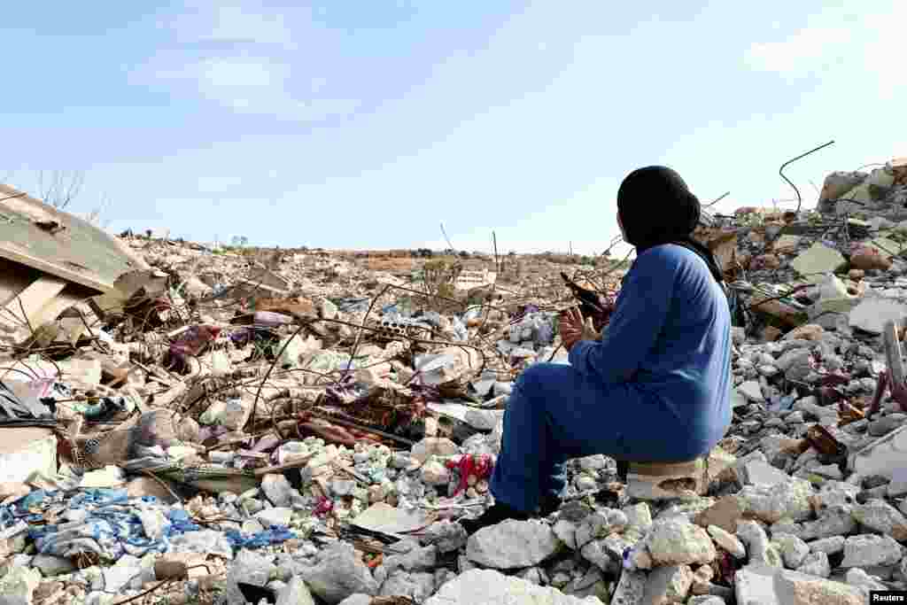 Lebanese woman Manar Feres, who returned to Kfar Kila following an Israeli troop withdrawal, sits on the wreckage of her damaged home near the border with Israel, in Lebanon on February 18, 2025.