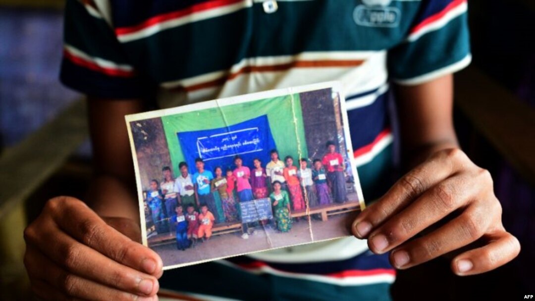 ဒုက္ခသည်စခန်းက ရိုဟင်ဂျာ လူငယ် Mohammad Ayaz က သူ့မိသားစုဝင် ဓါတ်ပုံကို ပြနေစဉ် (ဓါတ်ပုံ- AFP /MUNIR UZ ZAMAN) 
