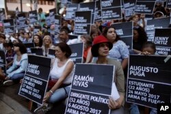 FILE - Anti-government demonstrators hold the names of people killed during months of deadly protests against Venezuelan President Nicolas Maduro, at a park in Caracas, Venezuela, Aug. 30, 2017.