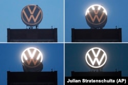 In this Monday, September 9, 2019 combiantion of four photos workers unveil the new company logo of the German car manufacturer 'Volkswagen' on top of the company's headquarters in Wolfsburg, Germany.