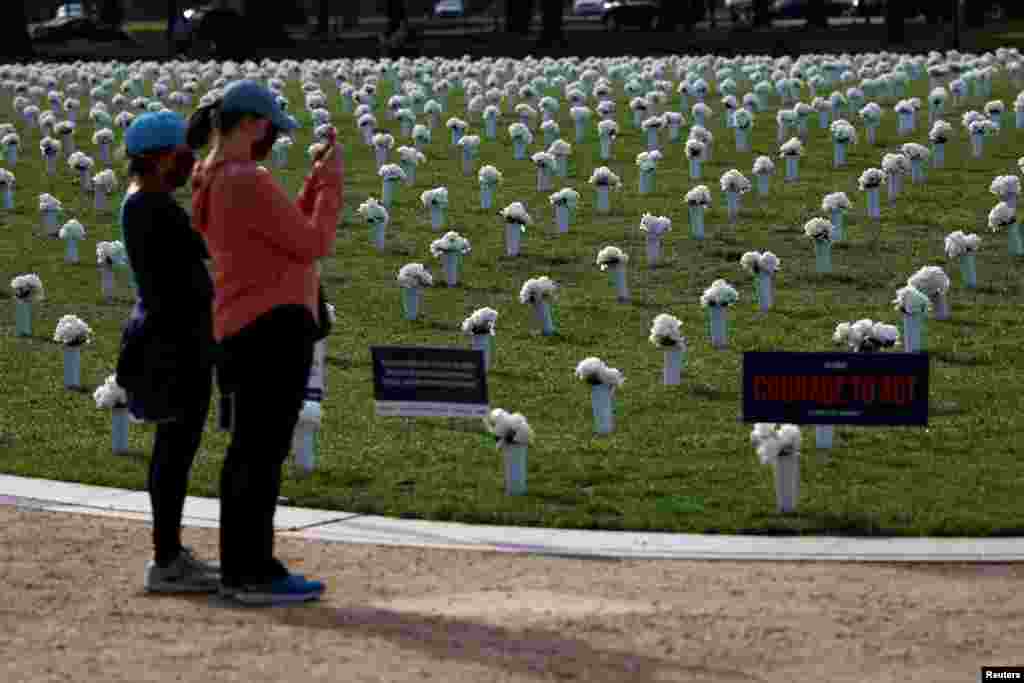 Visitors take pictures of the new Gun Violence Memorial, an installation featuring 38,000 silk white roses in 4,000 vases to commemorate the roughly 40,000 Americans who die annually in gun violence, on the National Mall in Washington, D.C.