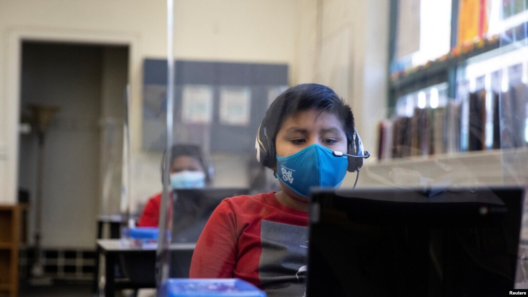 Chrystopher Camey Lopez uses a computer from a socially-distanced desk during an in-person hybrid learning day at the Mount Vernon Community School in Alexandria, Virginia, March 2, 2021.