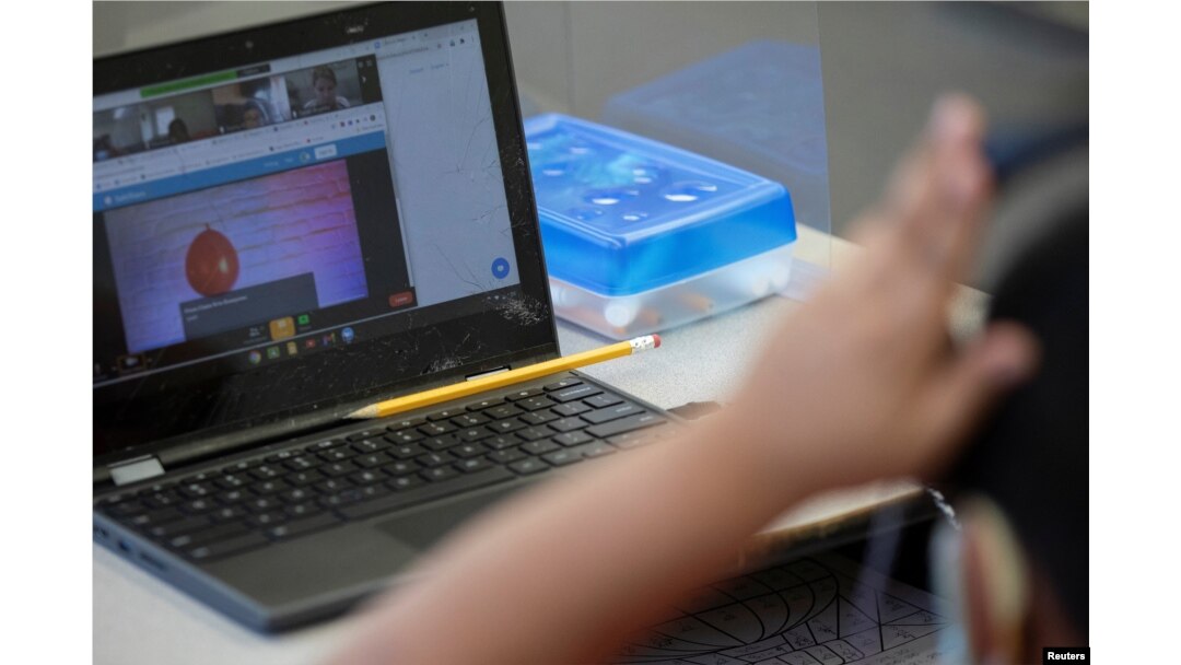 A student's pencil rests on a laptop during an in-person hybrid learning day at the Mount Vernon Community School in Alexandria, Virginia, March 2, 2021.