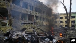 Un automóvil se incendia cerca de un hospital de maternidad impactado por los bombardeos rusos en Mariúpol, Ucrania, el 9 de marzo de 2022.