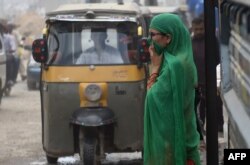 FILE - A Pakistani woman covers her face as she crosses a street in Karachi on September 27, 2016. (Photo by RIZWAN TABASSUM / AFP)