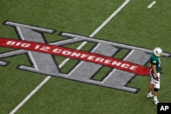 FILE - Baylor's Matt Ritchey stands by the Big 12 Conference logo on the field during the team's NCAA college football game against TCU in Waco, Texas, Oct. 13, 2012. (AP Photo/Tony Gutierrez, File)