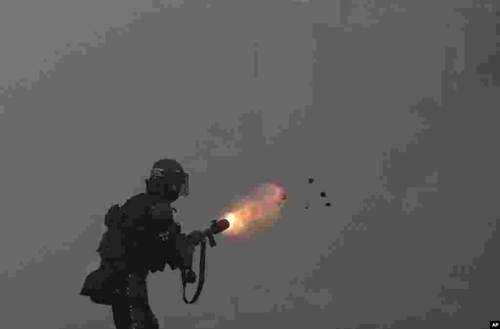 A police officer fires tear gas at protesters during a strike against tax reform in Cali, Colombia, May 3, 2021.
