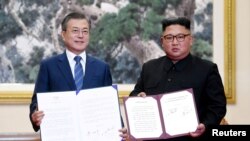 South Korean President Moon Jae-in and North Korean leader Kim Jong Un pose for photographs with the joint statement in Pyongyang, North Korea, September 19, 2018. Pyeongyang Press Corps/Pool via REUTERS TPX IMAGE.
