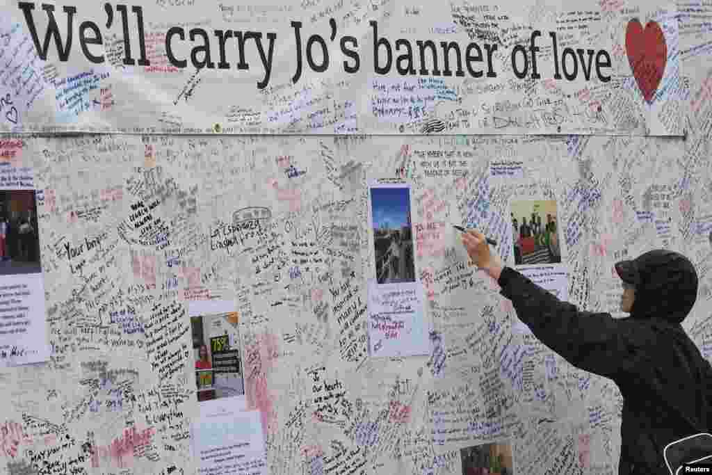 A man writes a tribute on a message board erected in memory of murdered Labour Party MP Jo Cox, who was shot dead in Birstall, at Parliament Square in London, Britain, June 20, 2016.