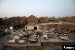 Men sleep on charpoy rope beds, early in the morning during a heatwave, on a roof in Jacobabad, Pakistan, May 15, 2022. (REUTERS/Akhtar Soomro)