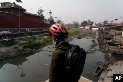 A man looks at the polluted Bagmati River from the Pashupatinath Temple in Kathmandu, Nepal, Monday, April 25, 2022. The Bagmati’s sludge oozes past the temple, declared a World Heritage Site by UNESCO in 1979, and several other sacred sites in the city. (AP Photo/Niranjan Shrestha)