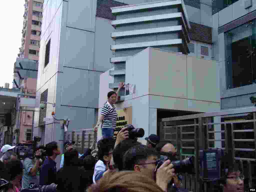 社會民主連線一成員將劉霞照片和抗議標語貼在中聯辦大門牆上(美國之音海彥拍攝)
